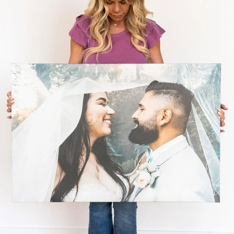 Woman holding a large custom canvas print of a smiling bride and groom