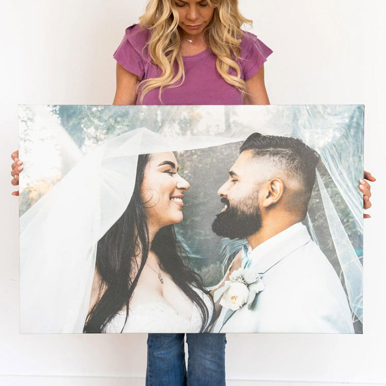 Woman holding a large custom canvas print of a smiling bride and groom